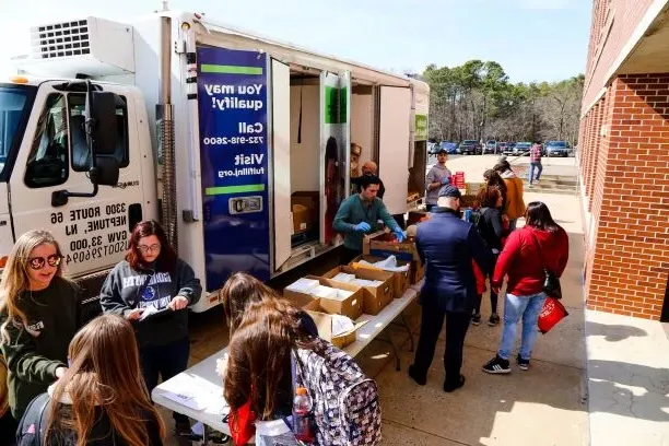 Group of students volunteering outside a big truck, taking donations